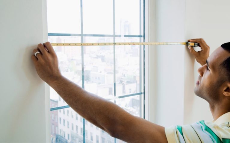 A man measuring the width of a window