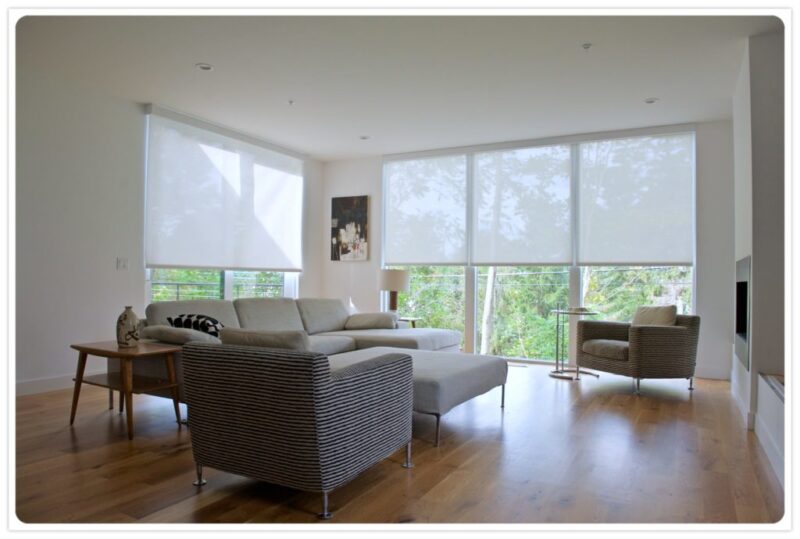 White Roller shades pulled halfway down in a living room full of natural light and wood floors